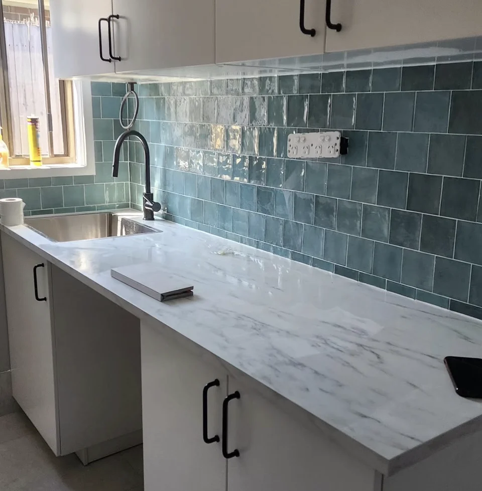 Blue-green handmade tiles on a completed kitchen splashback